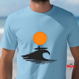 Light blue t-shirt with a graphic of a surfer on a wave and an orange sun, worn by a person.