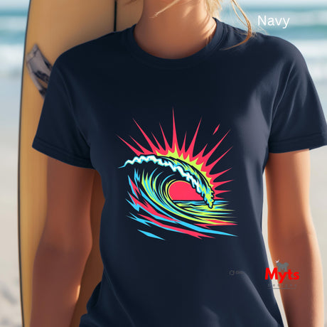 Person wearing a navy t-shirt with a colorful wave design, standing next to a surfboard on a beach.