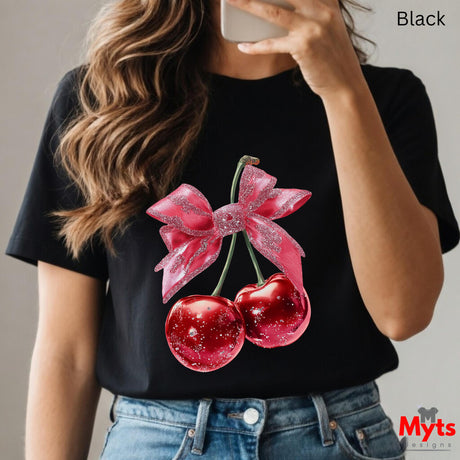 Person wearing a black t-shirt with red cherries and a pink bow design, holding a phone.