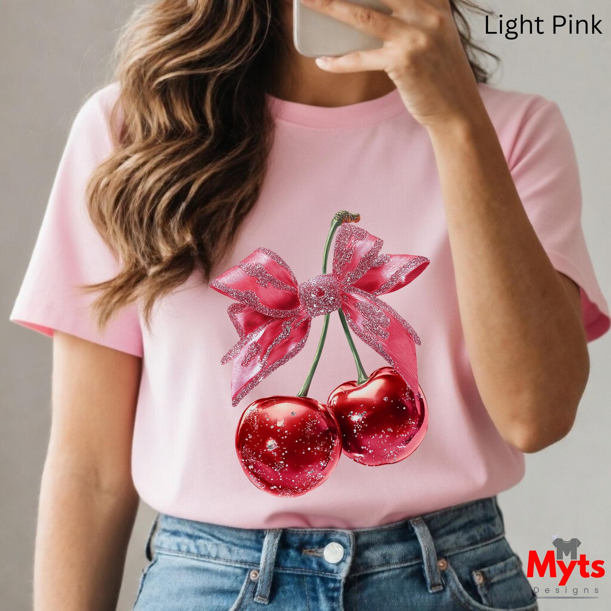 Person wearing a pink t-shirt with cherry design, holding a phone.