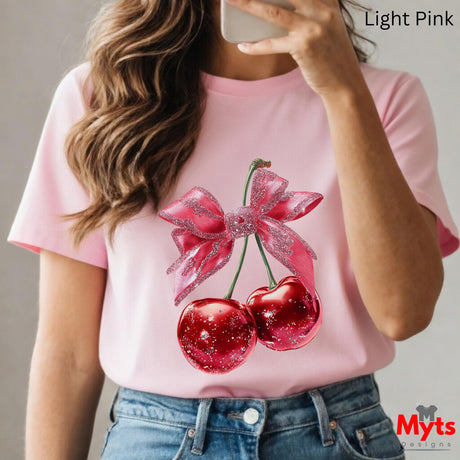 Person wearing a pink t-shirt with cherry design, holding a phone.