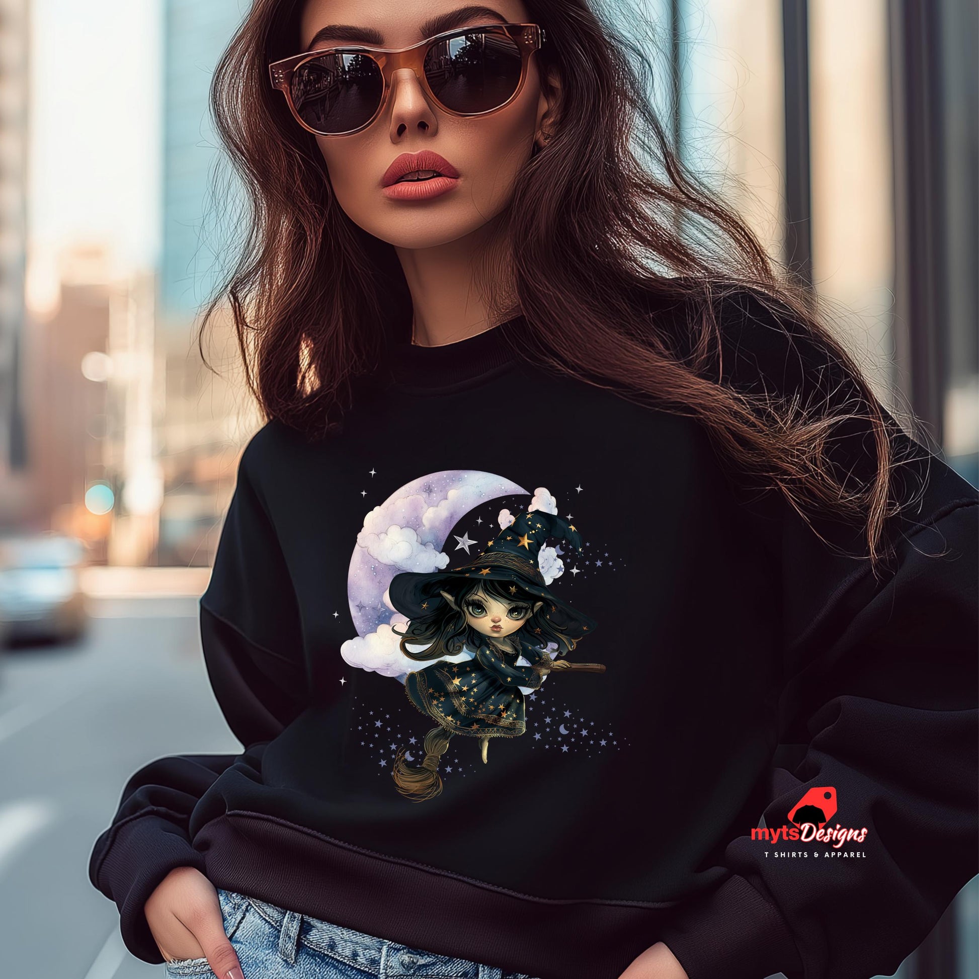 Woman wearing a black sweatshirt with a witch design and moon on a city street.