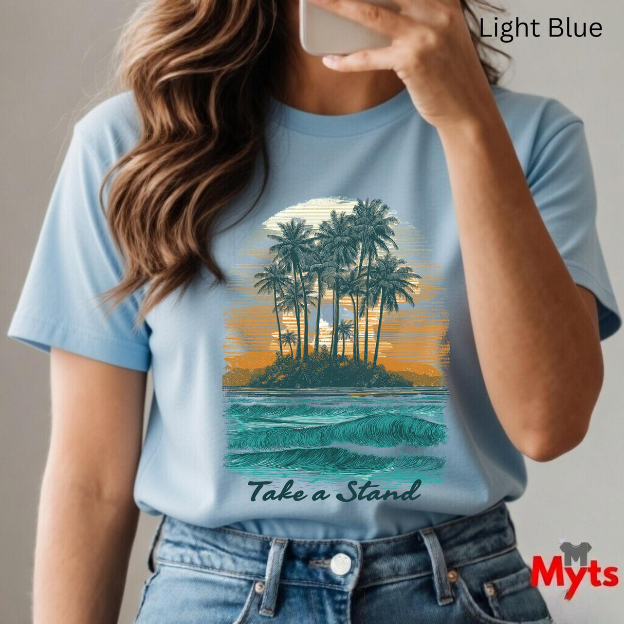 Person wearing a light blue t-shirt with a tropical island graphic and 'Take a Stand' text, holding a phone.