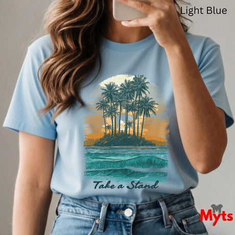 Person wearing a light blue t-shirt with a tropical island graphic and 'Take a Stand' text, holding a phone.