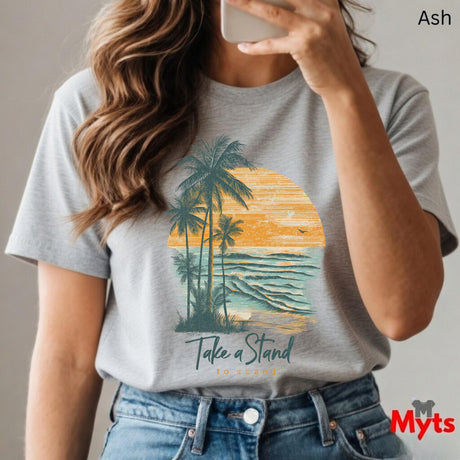 Person wearing a ash t-shirt with a palm tree and sunset design, holding a phone.