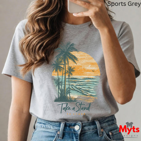 Person wearing a gray t-shirt with a palm tree and sunset design, taking a selfie.