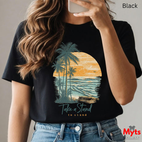 Person wearing a black t-shirt with a palm tree and sunset design, holding a phone.