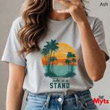 Person wearing a t-shirt with a palm tree and sunset design, text 'Take a Stand', and jeans.