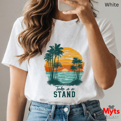 Person wearing a white t-shirt with a palm tree design and 'Take a Stand' text, holding a phone.