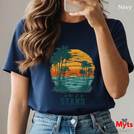 Person wearing a navy t-shirt with a palm tree design and 'Take a Stand' text, holding a phone.