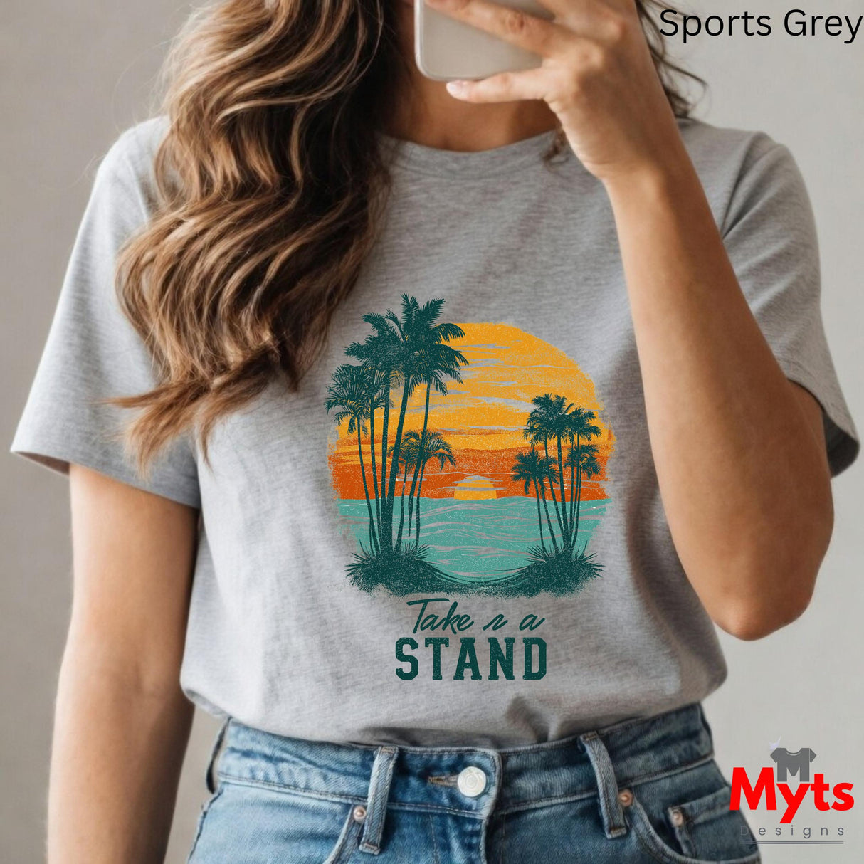 Person wearing a gray t-shirt with a tropical design and 'Take a Stand' text, holding a phone.