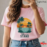 Person wearing a pink t-shirt with a palm tree design and 'Take a Stand' text, holding a phone.