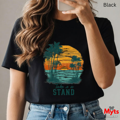 Person wearing a black t-shirt with a palm tree design and 'Take a Stand' text, holding a phone.