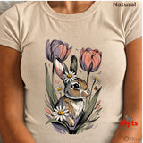 A person wearing a lNatural short-sleeve T-shirt with a large printed illustration of a rabbit surrounded by tulips and daisies. The top right corner reads 'Natural', and the bottom right shows the 'Myts Designs' and 'Grok' logos.