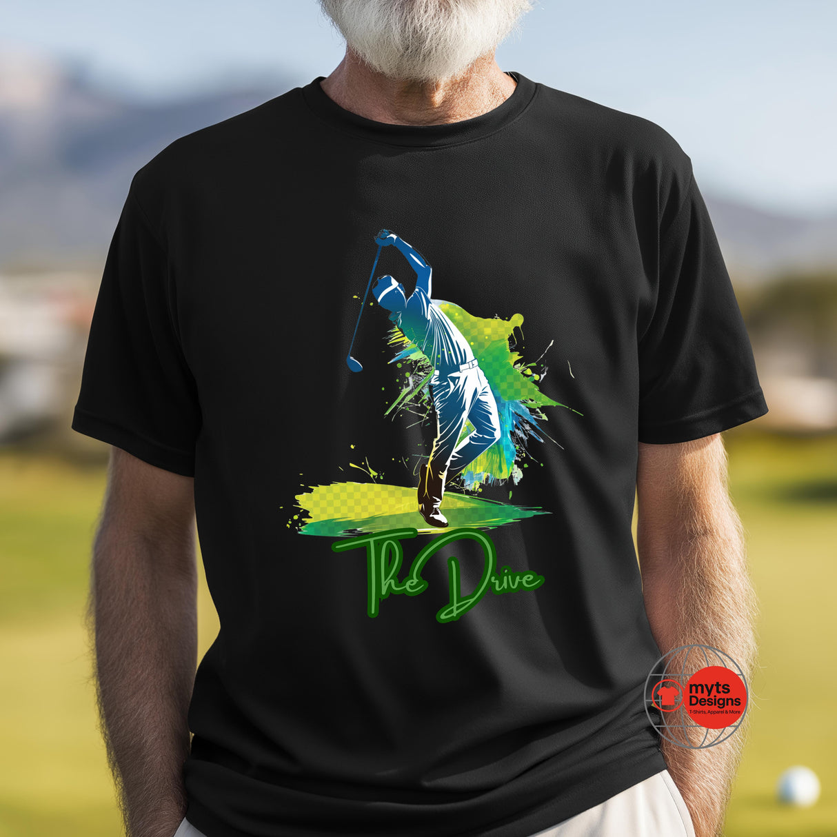 Person wearing a black t-shirt with a colorful graphic and 'The Drive' text on a golf course.