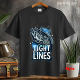 Dark Heather t-shirt with fish graphic and 'Tight Lines' text on a wooden surface with plants and a suitcase.