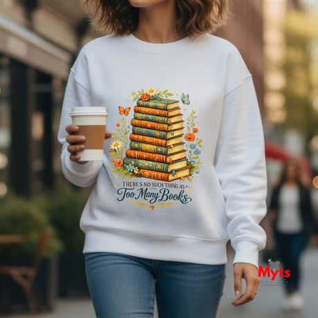 Person wearing a white sweatshirt with a book-themed design, holding a coffee cup.