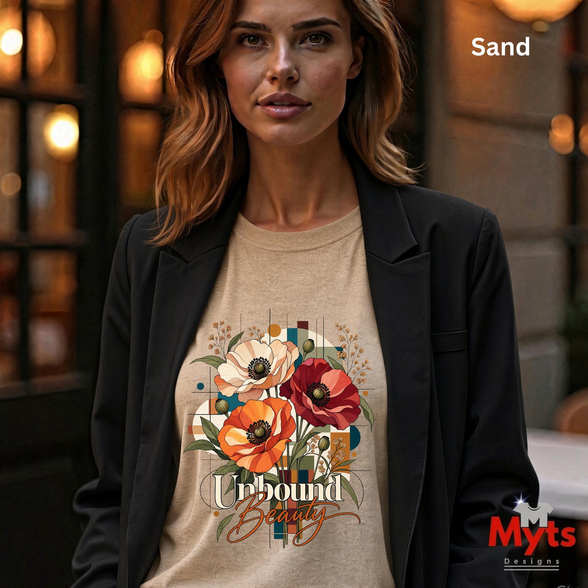 Woman wearing a sand Unbound Beauty graphic T-shirt with red, orange and cream poppy flowers, geometric accents and retro typography.
