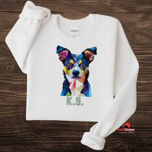 A white sweatshirt displayed on a wooden surface featuring a bold and colorful polygon art dog portrait with the text “K.9.” beneath it, designed by MytsDesigns.

