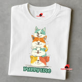 A folded white T-shirt featuring a colorful graphic of four stacked cartoon puppies in teal, orange, cream, and yellow shades with the words “Puppy Love” in playful green text below

