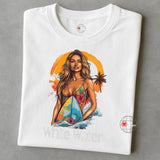 A folded WhiteT-shirt featuring a vibrant illustration of a confident woman in a floral bikini holding a surfboard with ocean waves and an orange tropical sunset in the background. Below the graphic is the text “White Water.”