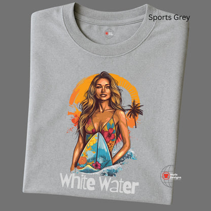 A folded grey T-shirt featuring a vibrant illustration of a confident woman in a floral bikini holding a surfboard with ocean waves and an orange tropical sunset in the background. Below the graphic is the text “White Water.” 