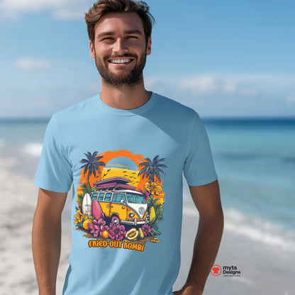 A man wearing a light blue T-shirt with a vibrant graphic of a retro yellow Kombi van, surfboards, tropical flowers, palm trees, and a bold orange sunset, on a beauitful beach