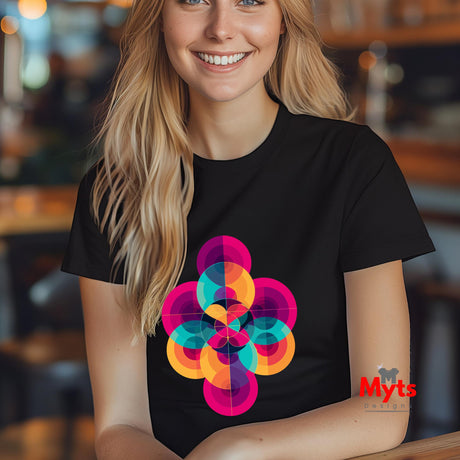 Woman wearing a black t-shirt with a colorful geometric design, sitting in a blurred indoor setting.