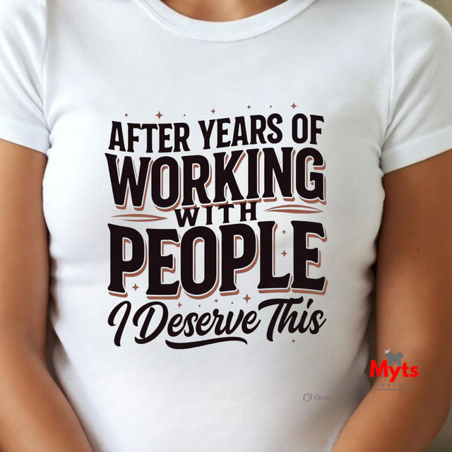 A white short-sleeve crewneck t-shirt with a humorous graphic that reads 'AFTER YEARS OF WORKING WITH PEOPLE I DESERVE THIS' in black and brown lettering. The t-shirt is shown on a model, with the model's arms and torso visible.