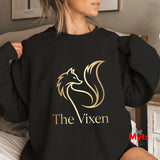Person wearing a black sweatshirt with 'The Vixen' logo in gold.