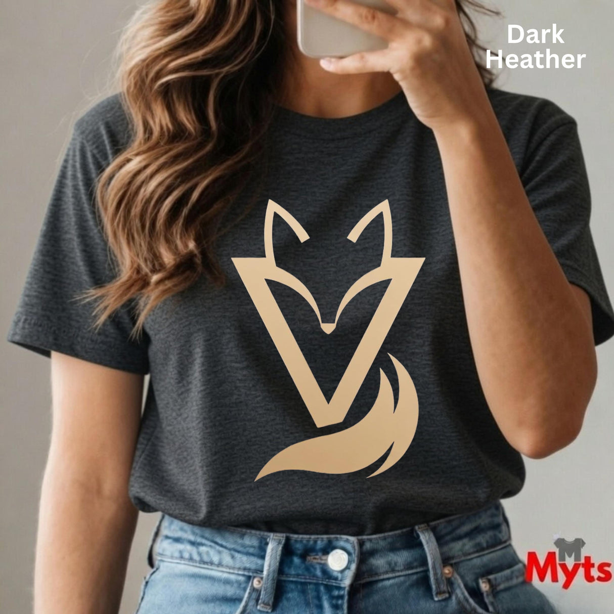 Woman wearing a Dark Heather Vixen minimalist fox graphic T-shirt featuring a modern gold-toned geometric fox symbol with a flowing tail design.