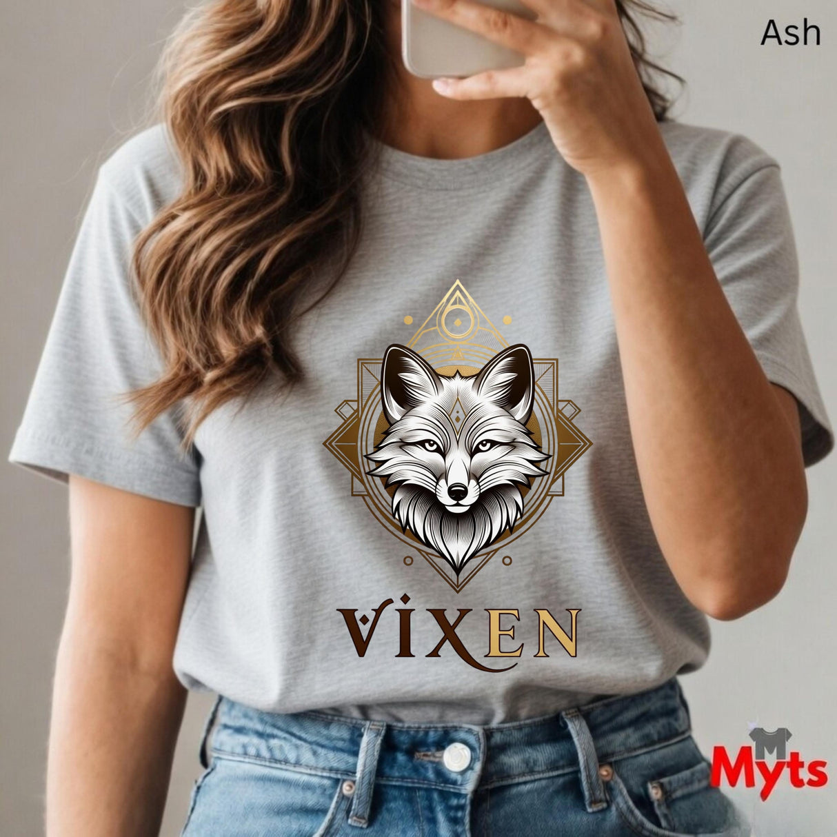 Person wearing a gray t-shirt with a fox design and 'Vixen' text, holding a phone.