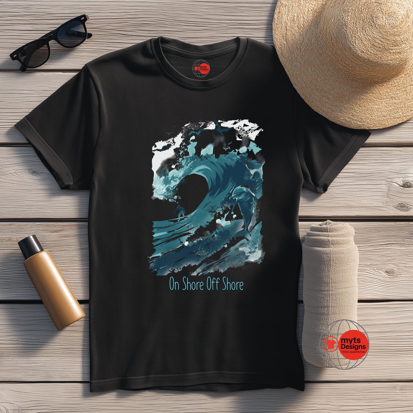 Black t-shirt with blue wave design and 'On Shore Off Shore' text, placed on a wooden surface with a hat, sunglasses, and water bottle.