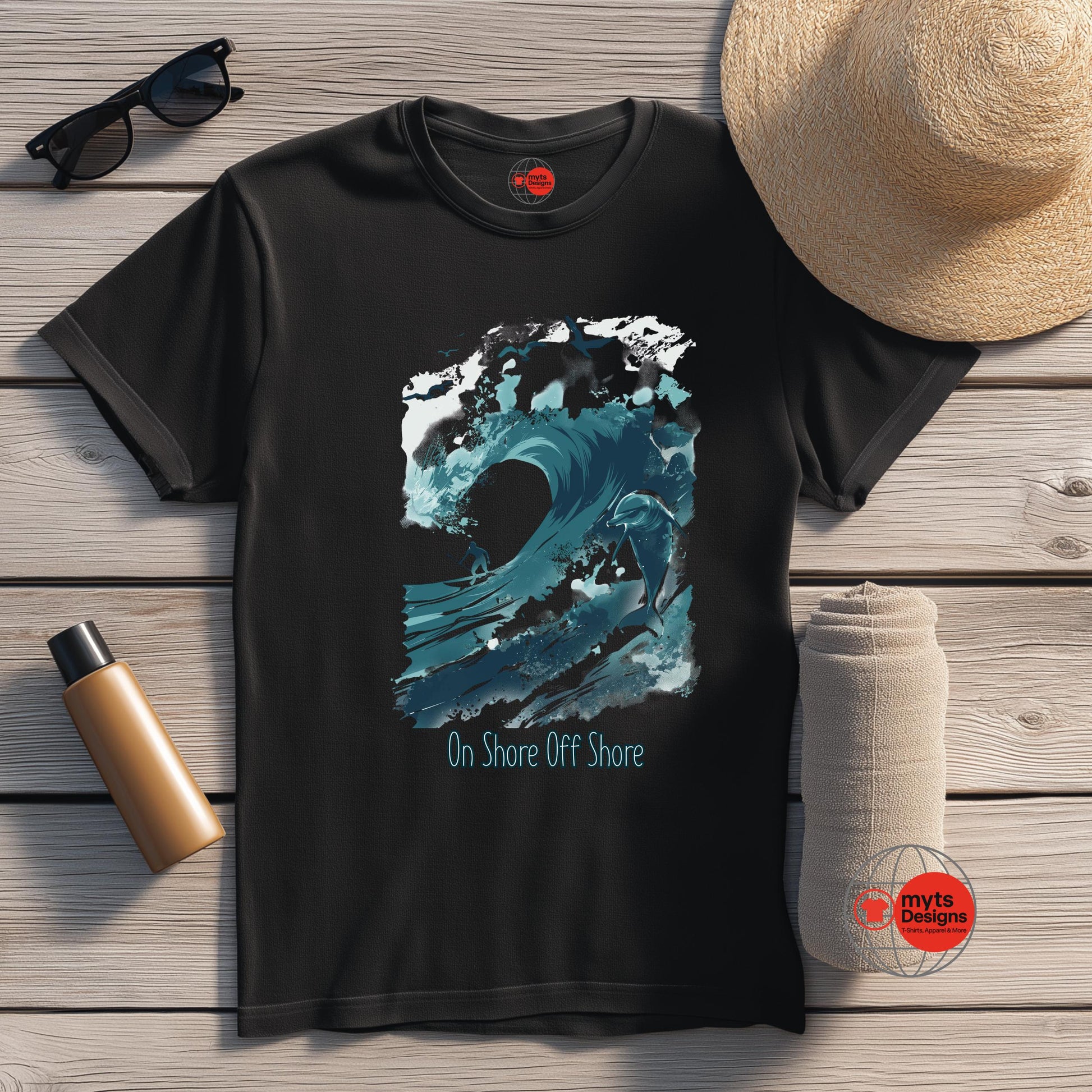 Black t-shirt with blue wave design and 'On Shore Off Shore' text, placed on a wooden surface with a hat, sunglasses, and water bottle.