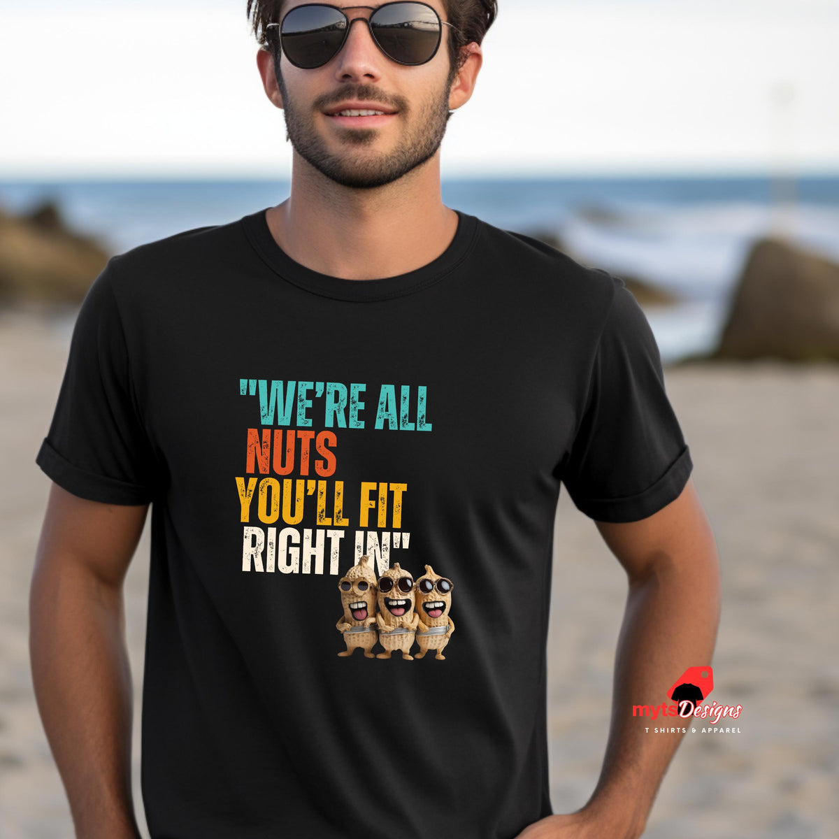 A man wearing sunglases and a black funny retro t-shirt at the beach