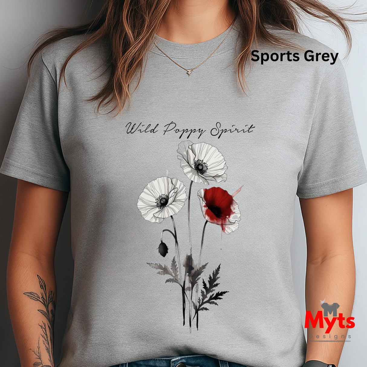 A woman wearing a Sports Grey crewneck T-shirt with a poppy graphic print. The graphic features three white poppies and one red poppy with black stems and leaves, and the text 'Wild Poppy Spirit' is printed above.ts