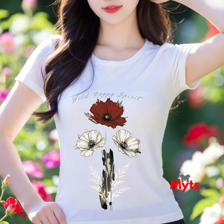 A woman wearing a white short-sleeve t-shirt with a graphic print of wild poppies and the text 'Wild Poppy Spirit'. The background is a blurred garden with green foliage and pink flowers.