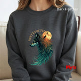 A person wearing a dark heather gray crewneck sweatshirt with a graphic of a wolf with teal, orange, and black feathers in front of a full moon, with the text 'NEXT EVOLUTION' above it. The sweatshirt has 'Dark Heather' text in white in the top right and a red 'Myts' logo in the bottom right.