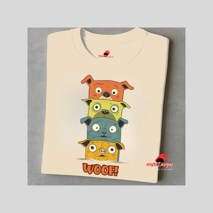 A folded neutral T-shirt featuring a quirky graphic of four stacked cartoon dogs in orange, yellow, teal, and golden tones with playful “WOOF!” text below the design.