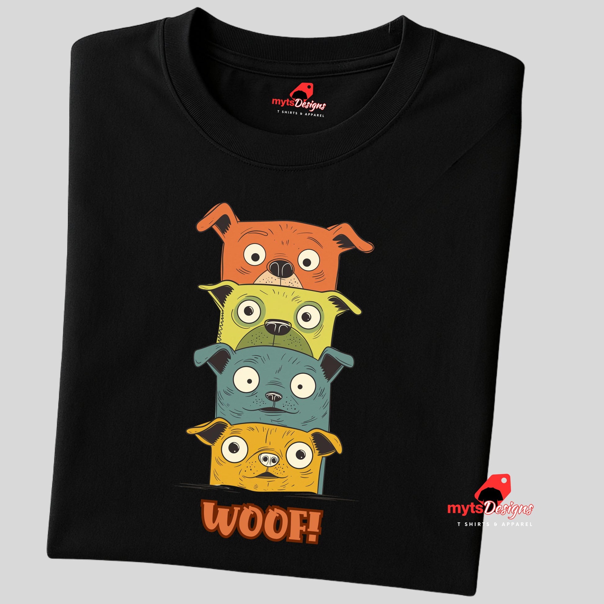 A folded black T-shirt featuring a quirky graphic of four stacked cartoon dogs in orange, yellow, teal, and golden tones with playful “WOOF!” text below the design.