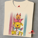 A folded sand T-shirt featuring a playful graphic of four stacked colorful dogs in yellow, red, and blue tones with the word “Woof?” in bold, cartoonish text below.

