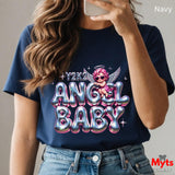 Person wearing a navy t-shirt with 'Y2K2 Angel Baby' design, holding a phone.