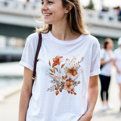 A woman wearing a white t-shirt with a floral design is outdoors by a waterfront.