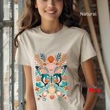 A woman wearing a natural beige t-shirt with a colorful butterfly and seashell graphic print, set against a softly blurred indoor background.