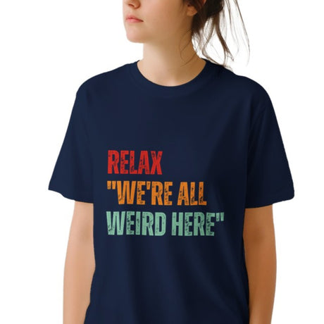A woman wearing a navy colored retro-style casual tee featuring bold distressed vintage typography reading “Relax — We’re All Weird Here,” printed on ultra-soft Gildan 64000 cotton.