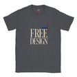 A dark heather gray t-shirt with a graphic print on the front reading 'FREE BY DESIGN' in beige serif letters, featuring a geometric flag design in red, white, and blue.