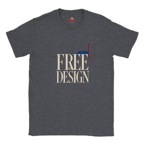 A dark heather gray t-shirt with a graphic print on the front reading 'FREE BY DESIGN' in beige serif letters, featuring a geometric flag design in red, white, and blue.