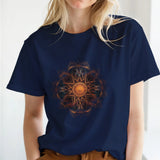 A woman wearing a navy blue t-shirt with a colorful mandala design in a bright room.