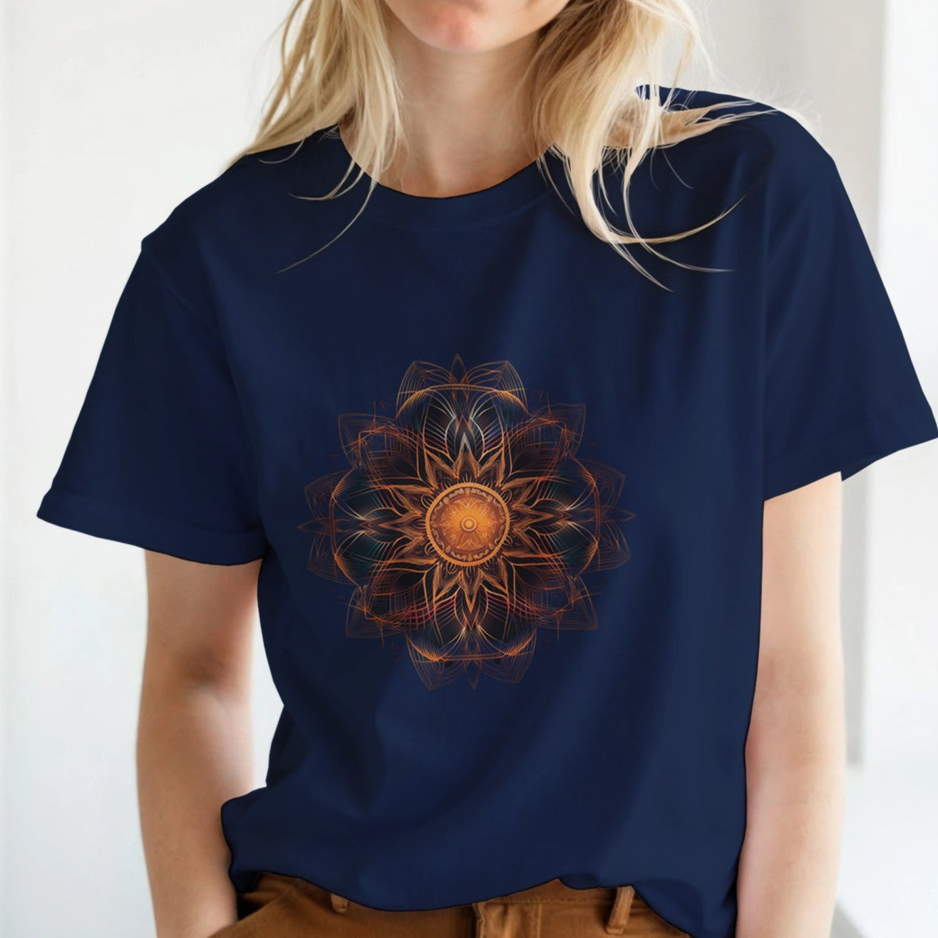 A woman wearing a navy blue t-shirt with a colorful mandala design in a bright room.