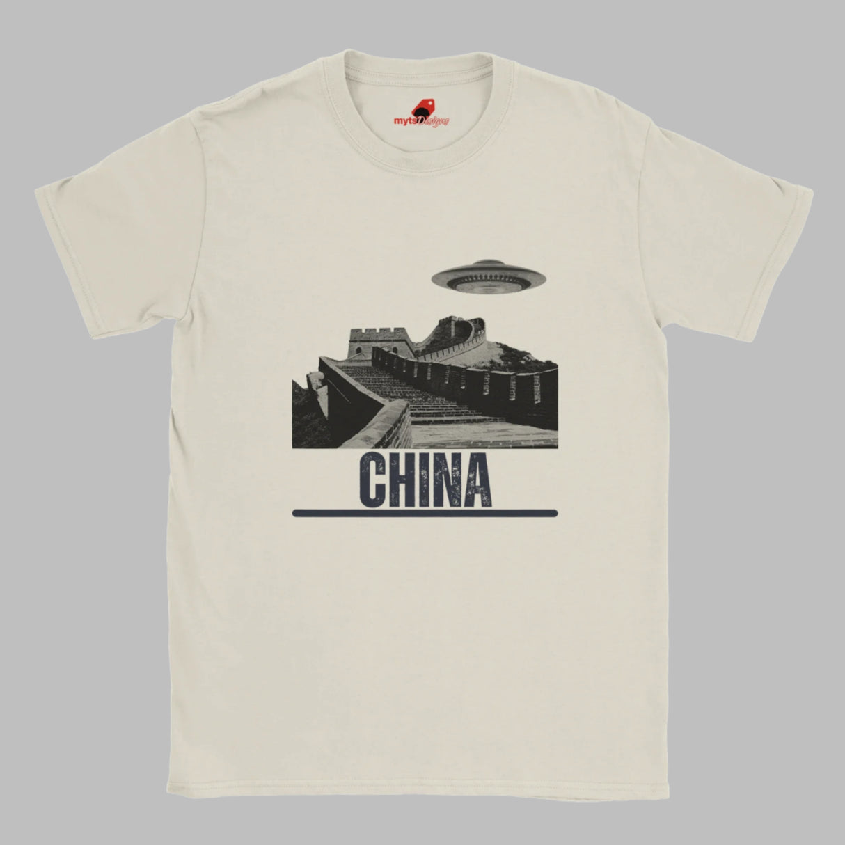 Sand coloured T-shirt with a vintage black-and-white Great Wall of China illustration and a UFO hovering above it, labeled ‘CHINA,’ designed by MytsDesigns.com”

